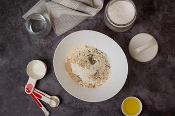 ingredients for making dough on a gray background in a white bowl