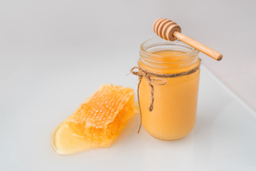 Honey pot with honey dipper and natural honeycomb .