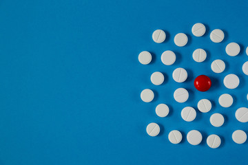 many white pills and one red on a blue background