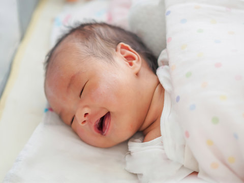 One month old baby in bed with dot blanket covering the mouth and rash on the cheeks The mouth of a newborn baby that does not have teeth