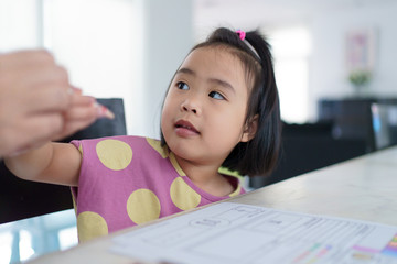 Kindergarten Asian girl doing homework at home. Ask the mother to help and teach.