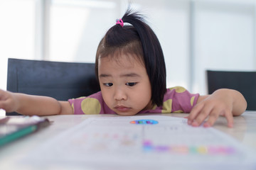 Kindergarten Asian girl doing homework at home. But homework is difficult, not fun and boring.