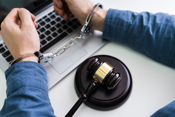 Person In Handcuffs And Gavel On Laptop
