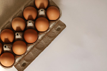 The container for eggs is corton. A dozen brown eggs per pack. Egg container on the side.