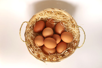 A wicker basket filled with chicken eggs. Brown eggs in a basket on a straw. Easter basket from the top.