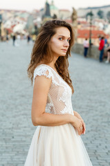 Naklejka premium Young bride poses on Charles Bridge. Bride in prague