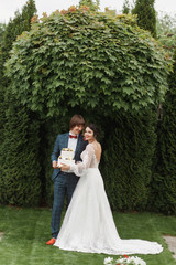 happy newlywed couple holding wedding cake on the lawn