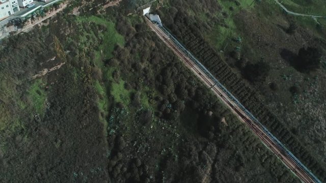 Tilt Down Hill Angle View Of Nazare (Nazar&eacute;), Funicular from the Houses Towards Green Hill With A Bird Flew By, Portugal.