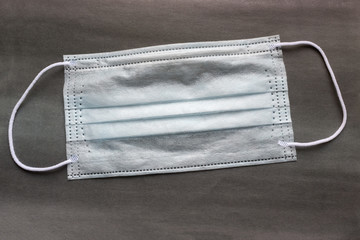 disposable mask on a dark background.  Protect the environment from the coronavirus. A rare product on the market of medical and pharmaceutical services. Security measure abroad