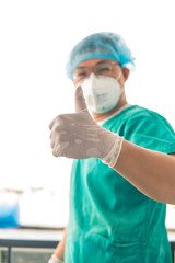 Young male doctor with stethoscope holding Coronavirus vaccine bottle and show thumbs up sign on white background. The scene is situated in controlled photography studio environment in front of white 