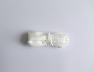 Folded face mask on white background . .Fasten the mask every time before throwing it into the trash