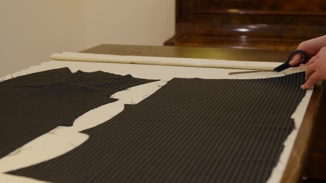 The tailor cuts a sewing pattern from the domette material with scissors. this Pre Shrunk Coton Bump fabric is used inside the bespoke canvas. Close-up of tailor's work.