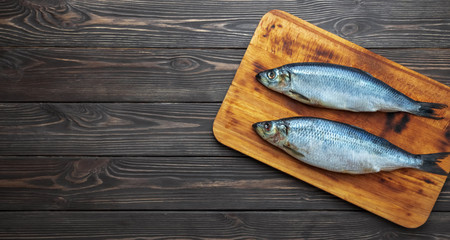 Seafood, pickled sea fish atlantic herring on a cutting board, wholesome diet food. Dark wooden background. Top view, copy space for text. Making a Dutch Herring Sandwich - Haringhandel