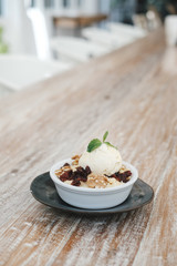 Apple crumble dessert with vanilla ice cream on the top on wooden table