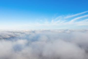 Aerial view of cloudscape layers of soft fluffy clouds over the city on a summer sunny day.