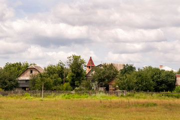 Green meadow with trees and houses far away. Small town