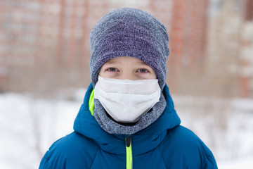 The danger of coronavirus. A boy on a walk walks in a medical mask on his face