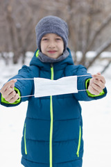 The danger of coronavirus. A boy on a walk walks in a medical mask on his face