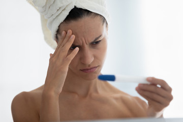 Close up frustrated by negative pregnancy test result woman in bathroom. After shower in morning...
