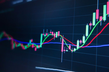 Stock market trading graph and candlestick chart on screen monitor background. Financial investment and economic concept.