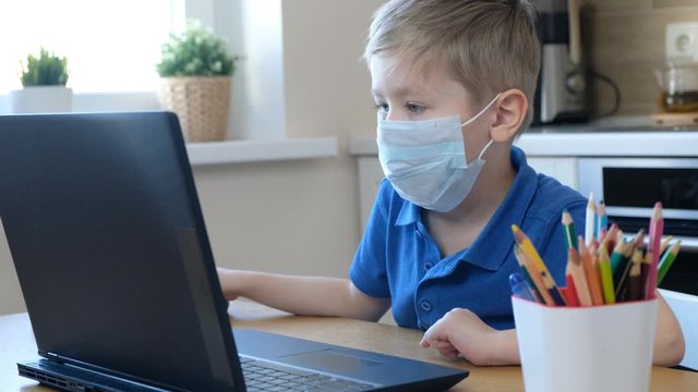 Distance learning online education. Cute caucasian boy doing homework on a computer while quarantine epidemia corona virus