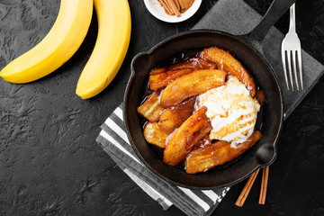 Homemade fried bananas foster with cinnamon and ice cream in cast iron pan