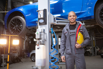 Cheerful African man smiling to the camera enjoying repairing cars at his workshop