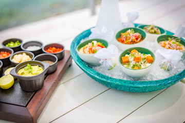 Ceviche gourmet sea food on white table. Delicious ceviche of shrimp with vegetables, spices and lime close up on a plate. Luxury outdoor restaurant with sea background and sunny weather