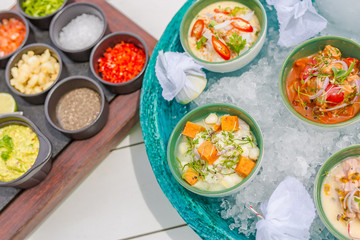 Ceviche gourmet sea food on white table. Delicious ceviche of shrimp with vegetables, spices and lime close up on a plate. Luxury outdoor restaurant with sea background and sunny weather