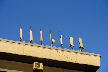 Mobile telephone radio network antennas on the building roof broadcasting signal over the city.