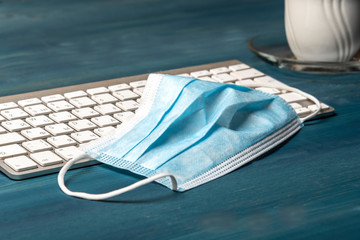 Medical mask on a computer keyboard on a blue table