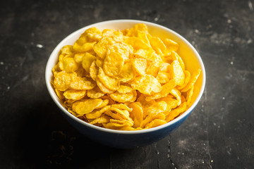 Tasty crispy corn flakes in bowl on the rustic background. Selective focus. Shallow depth of field.