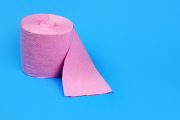 Roll of pink toilet paper on bright blue background. Space for text