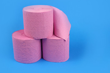 Pyramid of rolls of pink toilet paper on a bright blue background. Space for text