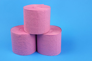 Pyramid of rolls of pink toilet paper on a bright blue background. Space for text