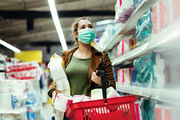 Woman with protective face mask buying toilet paper in the store during virus epidemic. © Drazen