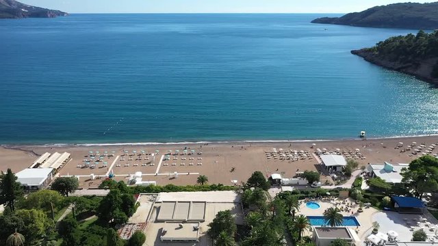 Sea beach fly over to the sea on a sunny day. Petrovac, Montenegro big beach with sand and a blue sea and summer sky.
