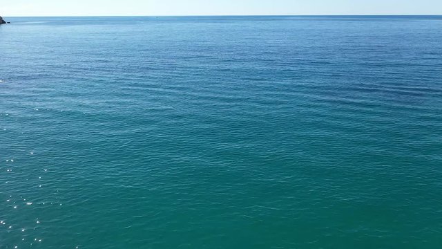 Fly over blue sea, with a man swimming and flying forward  to horisont. Sunny, summer day with a bright sky.