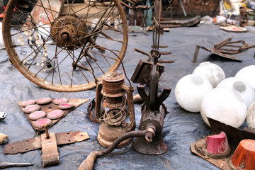 Old Vintage Rusty mincer, kerosine lamp, wheel and other used items on flea market.