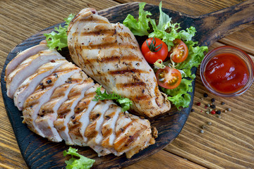 grilled chicken breast with fresh vegetables on a chopping Board