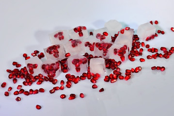 Frozen berries, Ice cubes and pomegranate granules seeds scattered on a white background
