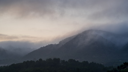 Hills covere in morning mist and low clouds as first days light breaks through
