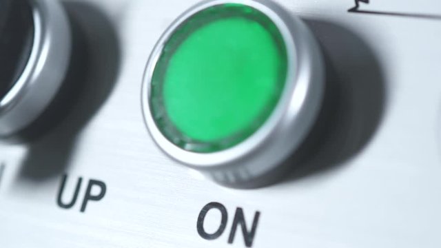 Green button power on. Finger pushing button. Start engine electrical equipment in industrial factory. Panel with green plastic round pressbutton. Beginning of work. Switch on. Turn on the electricity