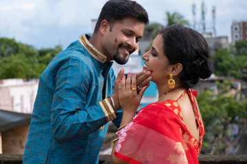 A brunette Indian Bengali romantic couple in traditional wear interacting between themselves on a...