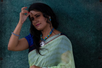 Portrait of a beautiful smiling brunette Indian Bengali woman in traditional wear sari posing on...