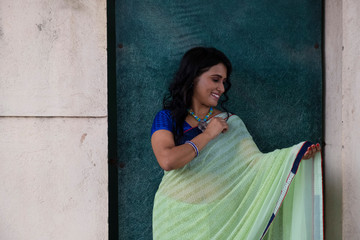 Portrait of a beautiful smiling brunette Indian Bengali woman in traditional wear sari posing on...
