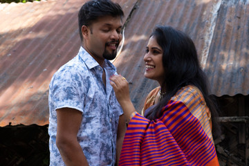 A brunette Indian Bengali romantic couple in traditional wear interacting between themselves in the...