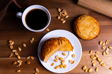 Fresh vegan cookie cakes with peanut butter, peanuts and a cup of coffee on a wooden board with copy space