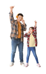 Happy Asian man and his little daughter listening to music on white background