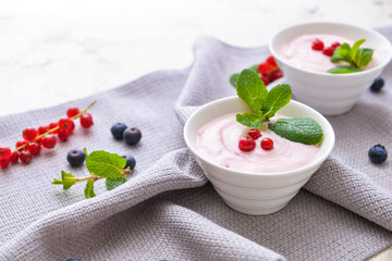 Bowls with tasty yogurt and berries on white background
